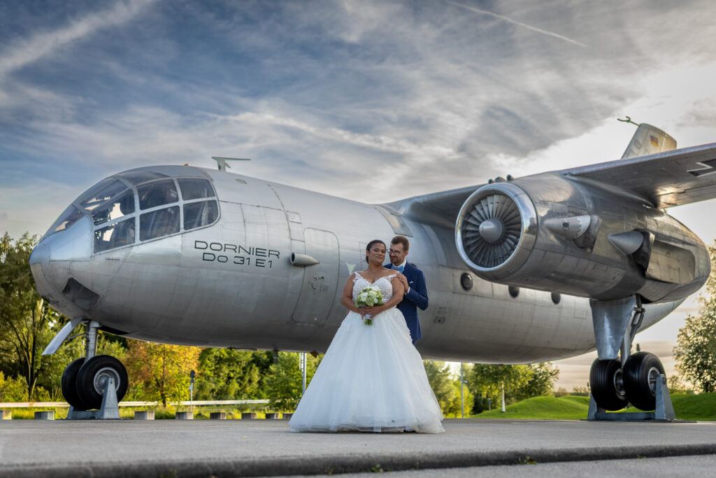 Brautpaar vor der Dornier Do 31 unter Wolkenhimmel – Hochzeit im Dornier Museum Friedrichshafen am Flughafen, Hochzeitsfotograf Bodensee