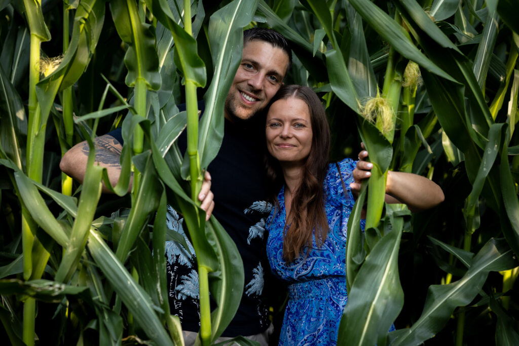 Jasmin und René schauen lachend aus dem Maisfeld – Kennenlernshooting am Guthügle bei Eschach